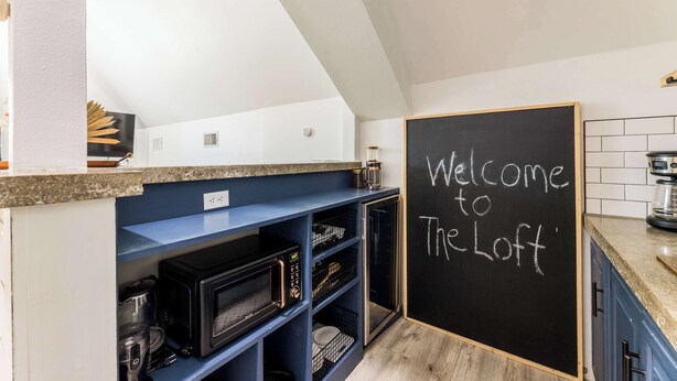 Uma cozinha com um quadro negro que diz 'Welcome to The Loft'.