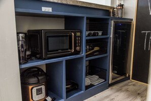 A compact kitchen with a microwave, coffee maker, and a small refrigerator. - The Loft | Modern Studio 5 Min to Downtown (Bentonville)