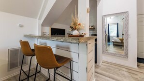 Uma cozinha com área de bar, dois banquetes, um espelho grande e vista para o quarto vizinho.