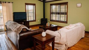 A living room with a sofa, a television, a fireplace, and a window with blinds.