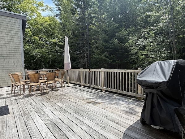 A wooden deck with outdoor furniture and a grill.