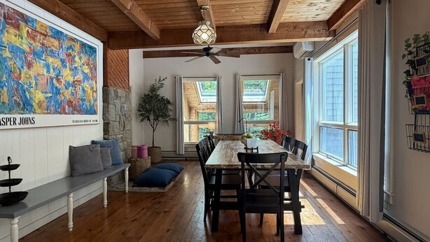 A dining area with a wooden table and chairs, a ceiling fan, and large windows with curtains. - 5BR near Park & Downtown Bar Harbor! [North Lodge] (Bar Harbor)