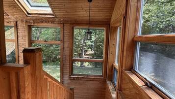 A wooden interior with large windows, a staircase, and a hanging lantern.