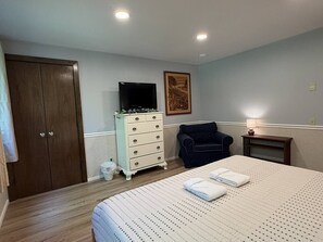 Ein Schlafzimmer mit Bett, Kommode, Stuhl und Fernseher.