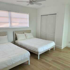A bedroom with two beds, a ceiling fan, and a door. - Gorgeous 4-bedroom house with AC in lively Hollywood (Hollywood)