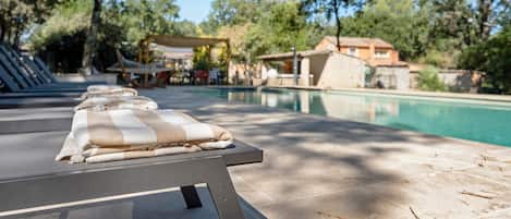 A poolside area with lounge chairs, a pool, and surrounding trees.