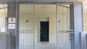 Un ingresso recintato con cancello in metallo, una porta e un piccolo tappetino all'ingresso.