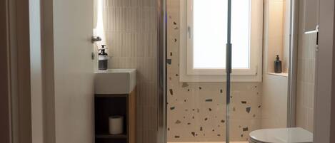 Une salle de bain moderne équipée d’une douche, de toilettes et d’un lavabo.