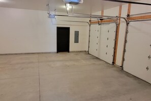 A spacious indoor area with a concrete floor, a black door, and a white wall with metal fixtures.