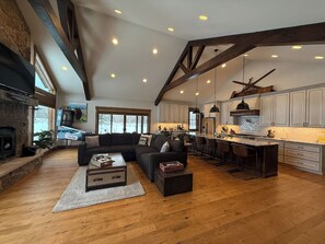 A spacious living area with a fireplace, a large sofa, and a kitchen with bar seating.