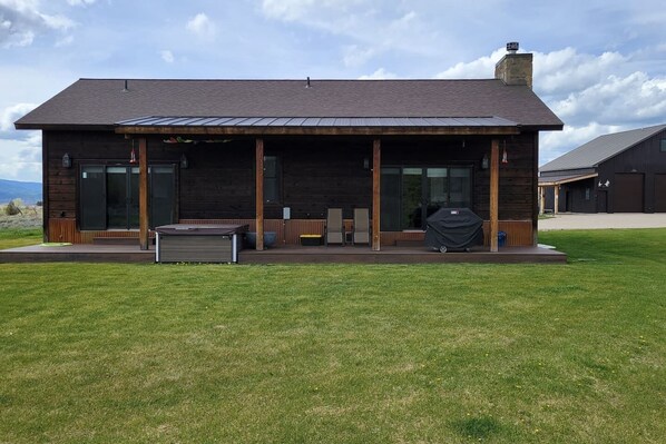A modern wooden building with a covered patio area, large windows, and a chimney.