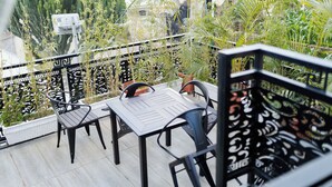 Un balcon agrémenté d’une table et de chaises, entouré de plantes en pot et orné d’une rambarde décorative.