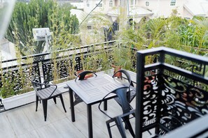 A balcony with a table and chairs, surrounded by potted plants and a decorative railing.