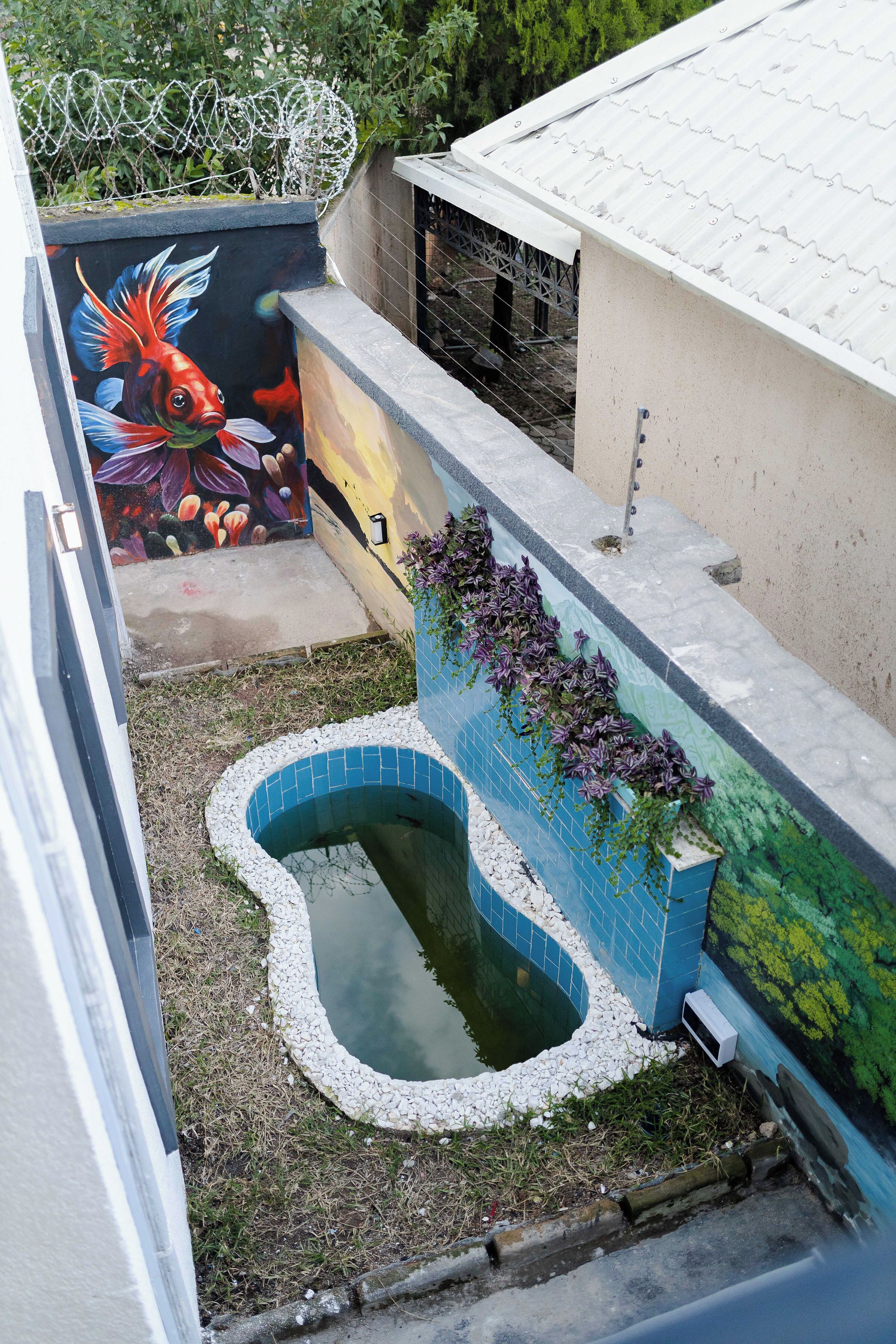 Terraço com piscina, um mural e um jardim.
