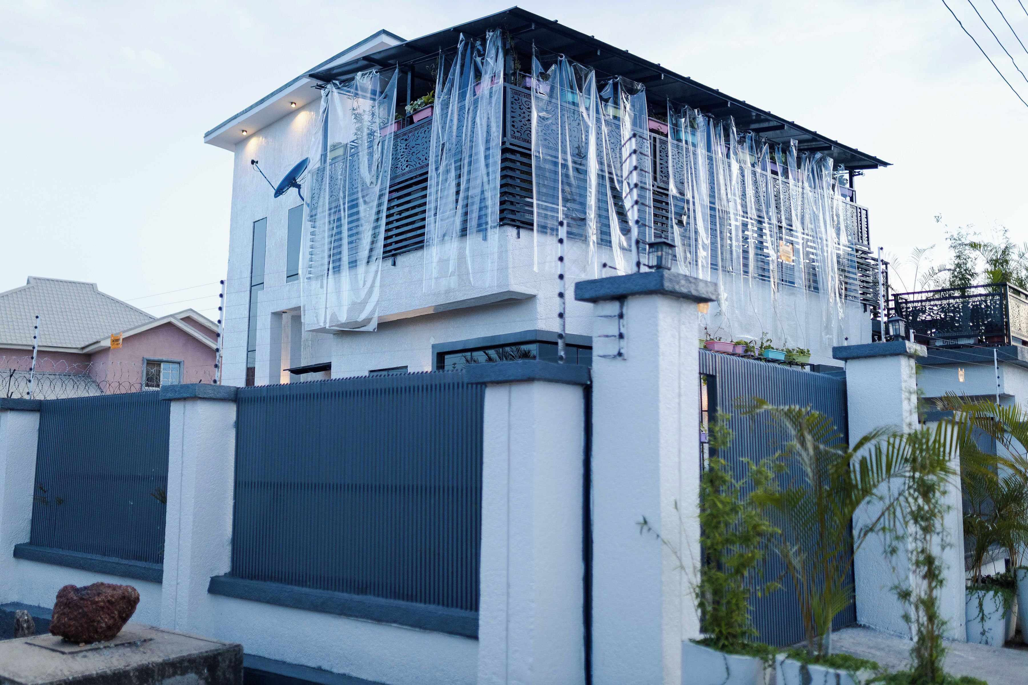 Une maison moderne à deux étages dotée d’un balcon recouvert de plastique.