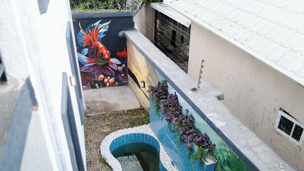 Une ruelle étroite agrémentée d’un élément décoratif aquatique aux carreaux bleus et d’une fresque colorée sur le mur.
