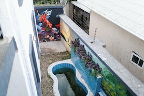 Un estrecho callejón con una fuente de agua de azulejos azules y un mural colorido en la pared.