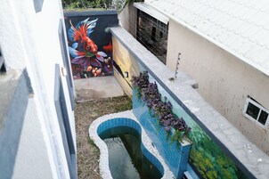 Uma passagem estreita com uma fonte de água em azulejos azuis e um mural colorido na parede.