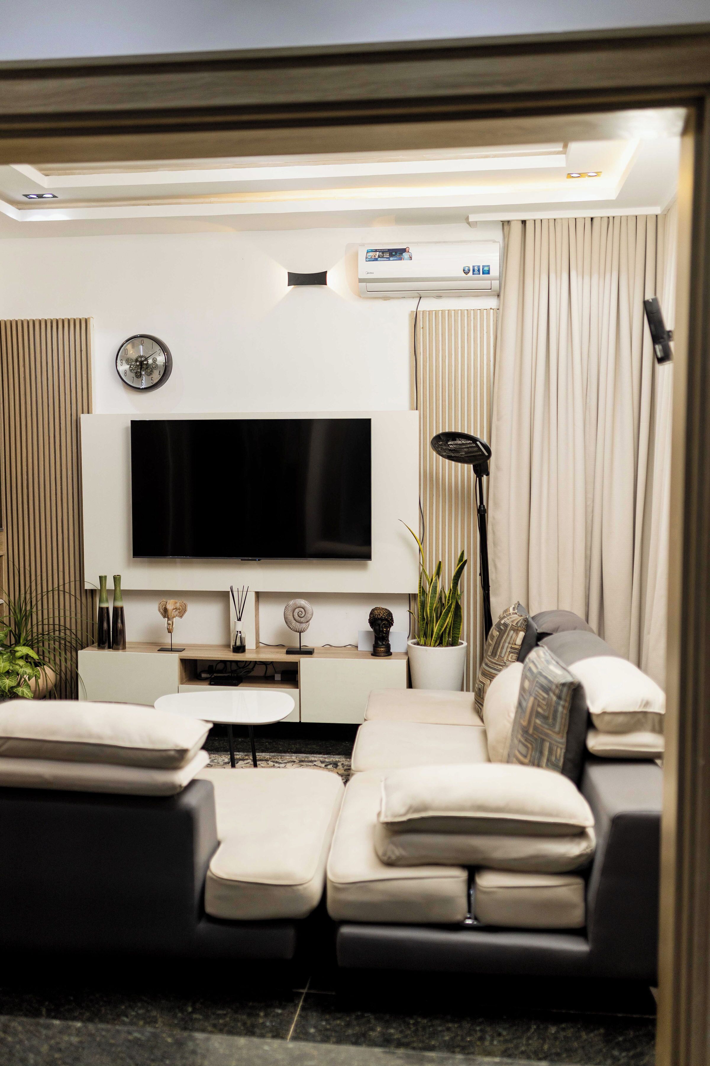 Un salon moderne avec un téléviseur à écran plat, un canapé, une table basse et un lampadaire.
