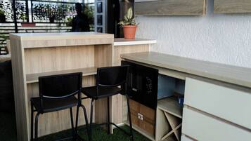 Una pequeña cocina con encimera de madera, dos sillas negras y un microondas.