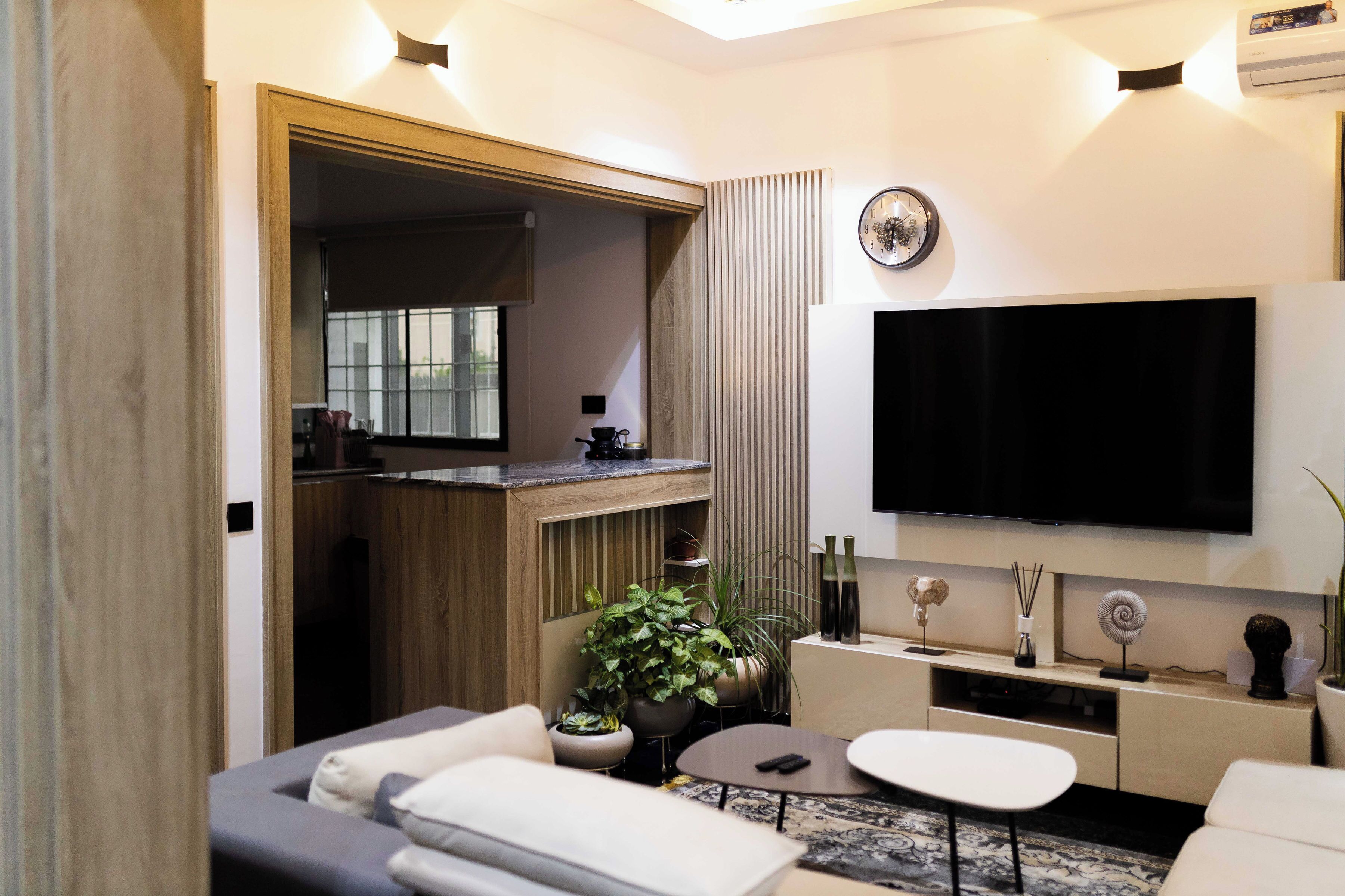 Una sala de estar moderna con un televisor de pantalla plana, un sofá, una mesa de centro y una pequeña cocina con microondas.