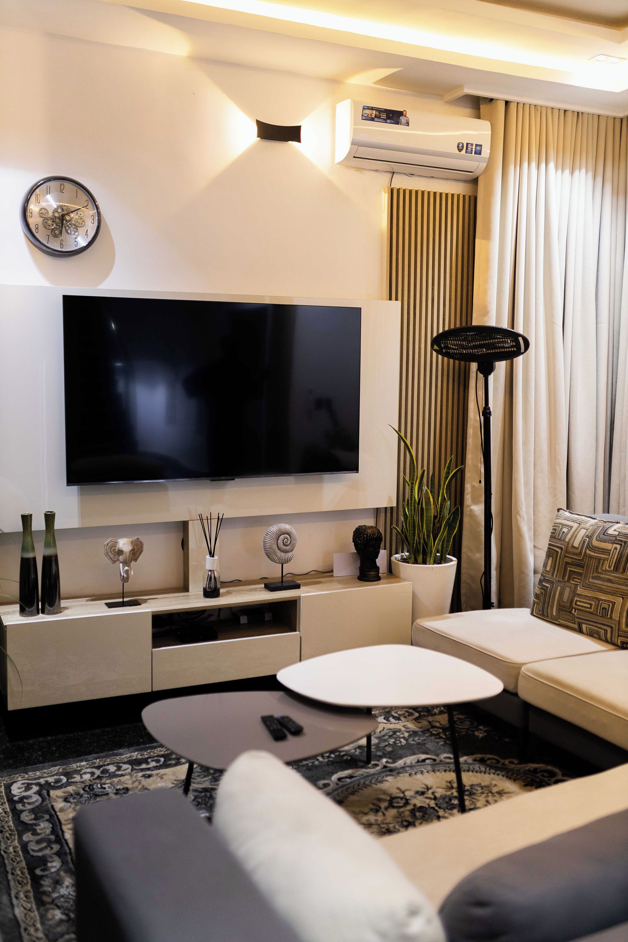 Una sala de estar moderna con una televisión de pantalla plana, un sofá, una mesa de centro y una planta decorativa.