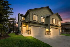 A two-story house with a garage, a well-maintained lawn, and a stone foundation. - Teewinot Townhome - Yellowstone, Targhee, Tetons (Victor)