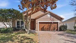 Ein Wohnhaus mit Garage, Auffahrt und einem Baum mit Herbstlaub.