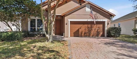 Une maison d’habitation avec un garage, une allée et un arbre aux feuilles d’automne.