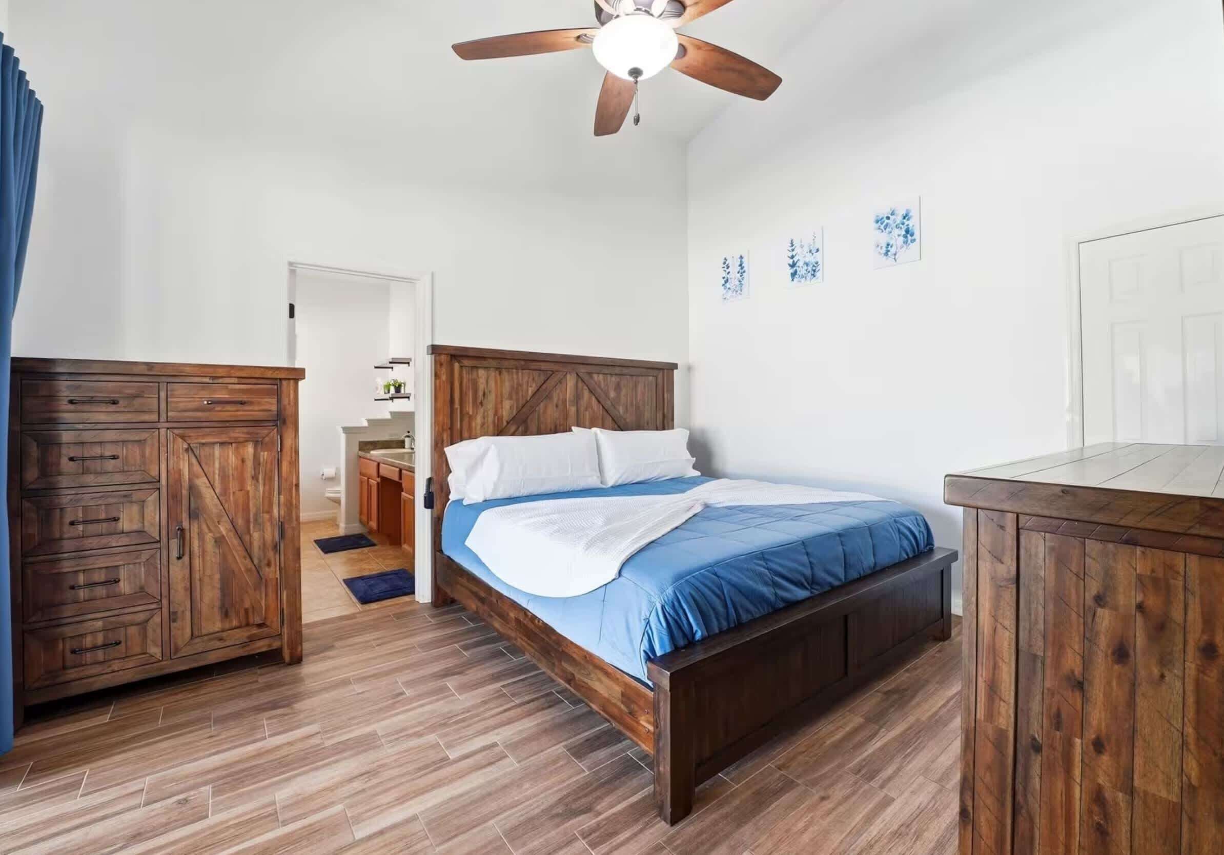 A bedroom with a wooden bed, a nightstand, a wardrobe, and a ceiling fan.