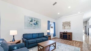 Ein modernes Wohnzimmer mit einem blauen Sofasatz, einem Holztisch und einem gemusterten Teppich.