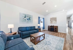 A modern living room with a blue sofa set, a wooden coffee table, and a patterned rug. - Bridgeford Splash Retreat (Davenport)