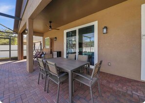 An outdoor patio with a table and chairs, a ceiling fan, and a glass door leading to a covered area. - Bridgeford Splash Retreat (Davenport)