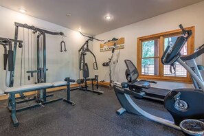 A gym with various exercise equipment, a bench, and a window with a view of trees. - Quiet condo near Targhee, Yellowstone, and Tetons. (Driggs)