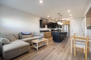 A modern apartment with a living room, kitchen, and dining area. - Teton Hideout - Sauna, AC, Garage (Driggs)