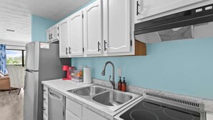 A modern kitchen with white cabinets, a stainless steel sink, and a built-in oven. - PCB Beach Home With Gulf Access, Pool, and More (Panama City Beach)