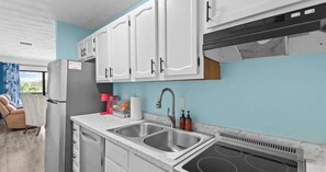 Eine moderne Küche mit weißen Schränken, einer Edelstahl-Spüle und einem eingebauten Backofen.