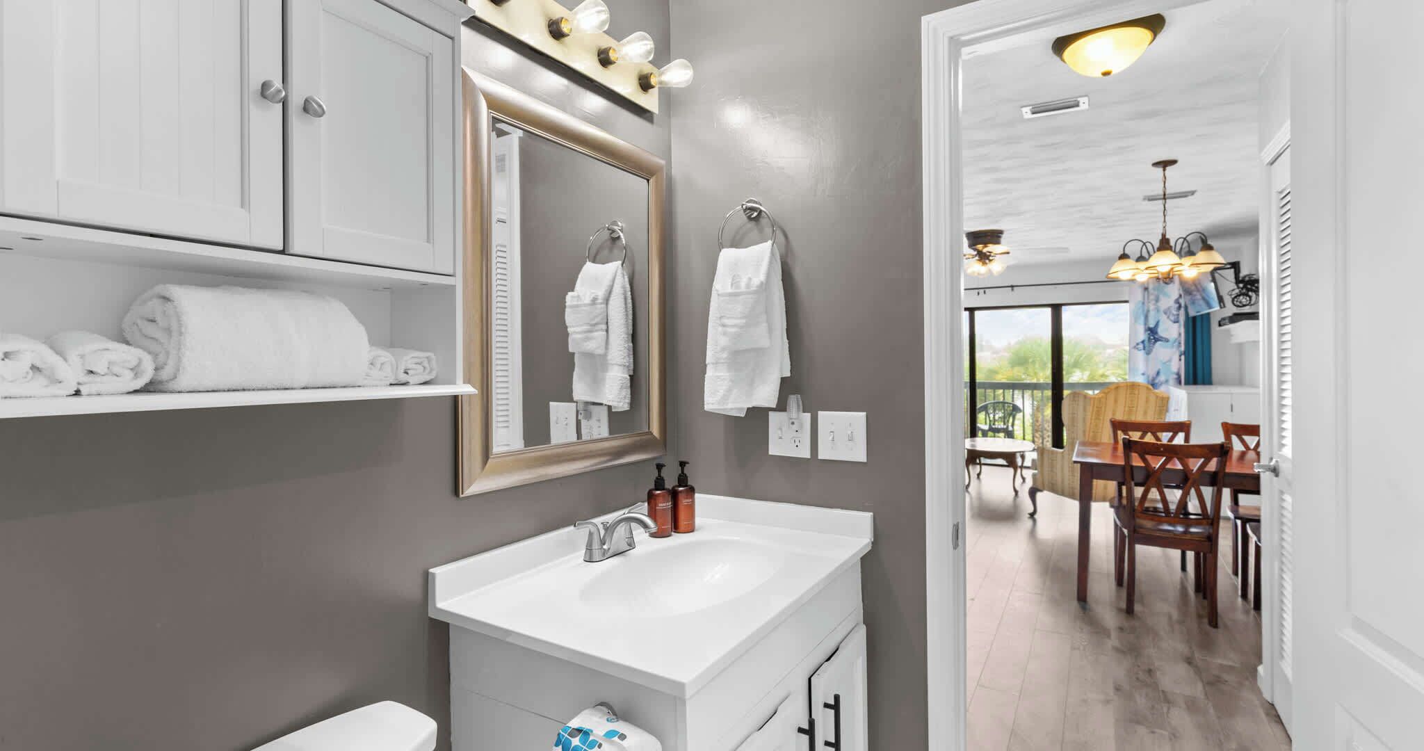Un baño moderno con tocador, un espejo grande y toallas en un estante.