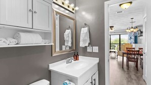A modern bathroom with a vanity, a large mirror, and towels on a shelf. - PCB Beach Home With Gulf Access, Pool, and More (Panama City Beach)