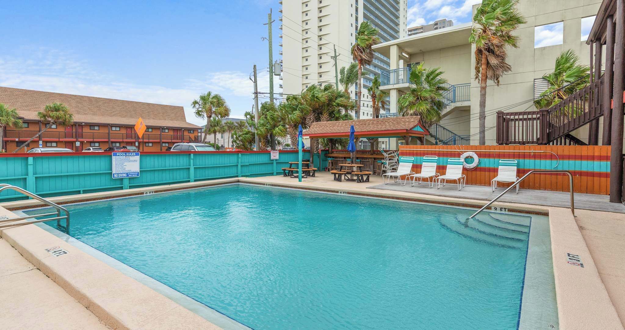Ein Swimmingpool mit Liegestühlen und einer überdachten Sitzgruppe.