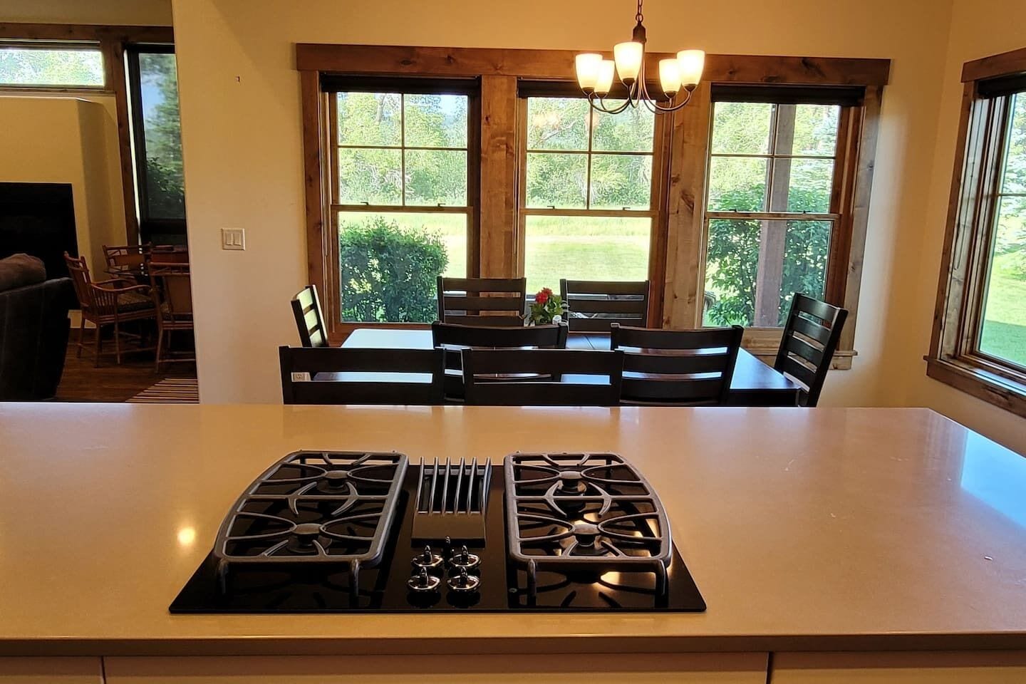 Una cocina con una isla central, dos estufas a gas y un comedor con sillas y una mesa.