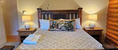 A bedroom with a wooden headboard, two bedside lamps, a bed with patterned bedding, and a ceiling fan.