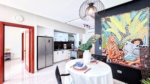 A modern kitchen with a refrigerator, cabinets, and a dining area with a table set for two. - Walking 2 Beaches, Dining, Shop, Fun, Nightlife (Punta Cana)