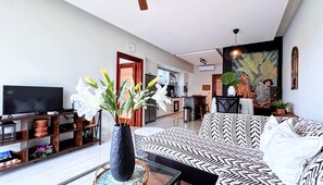 A living room with a sofa, a television, and a large vase of flowers. - Walking 2 Beaches, Dining, Shop, Fun, Nightlife (Punta Cana)
