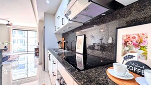 A modern kitchen with a black countertop, stainless steel appliances, and a framed floral artwork. - Walking 2 Beaches, Dining, Shop, Fun, Nightlife (Punta Cana)