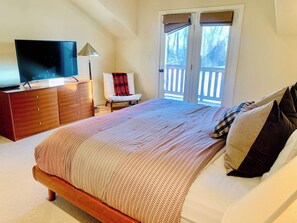 A bedroom with a bed, a television on a dresser, a chair, and a window with a view. - Mountain Town Getaway on Teton Creek (Driggs)