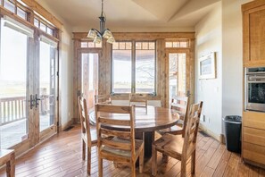 Ein Holzespeisesaal mit Stühlen, einer Chandelier und Blick durch große Fenster.
