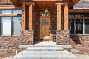 Ein Holzhaus mit Steinaußenseite, einer Haustür mit Glasscheiben und der Hausnummer 6426 an der Wand.