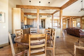 Ein geräumiger Essbereich mit Holztisch und -stühlen, im Hintergrund eine Küche und ein Wohnzimmer mit einer Ledersofa.