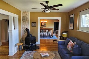A living room with a fireplace, a ceiling fan, and a dining area with a table and chairs. - Downtown Driggs base for Yellowstone/Grand Teton (Driggs)